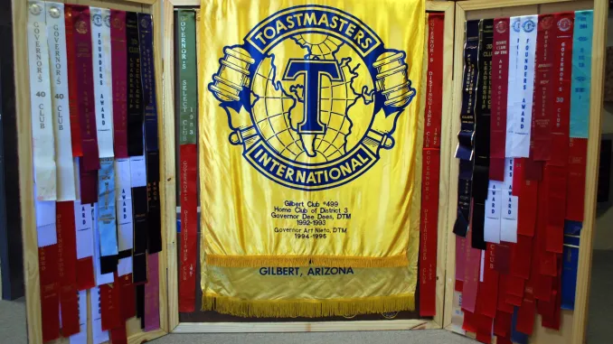 The Gilbert Toastmasters Club #499 banner, flanked by district ribbons earned over nearly five decades